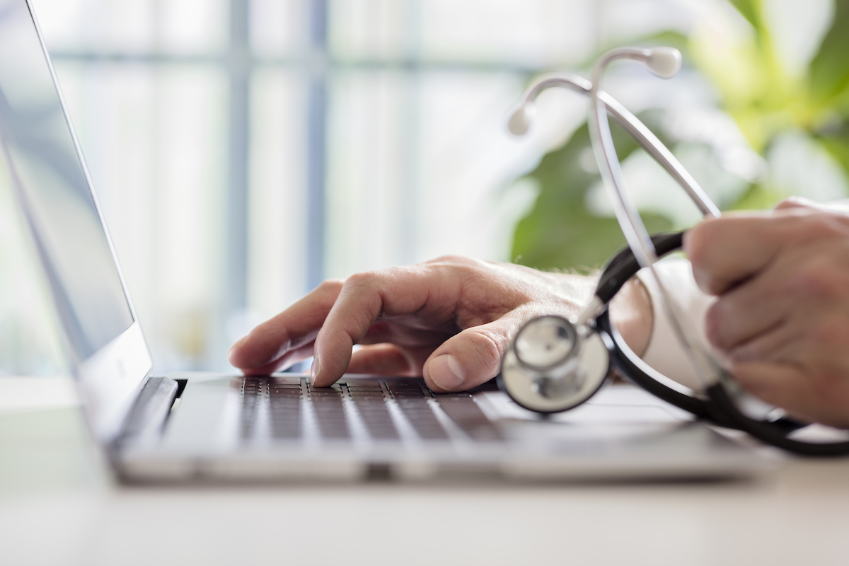 Doctor entering patient notes on laptop in surgery Doctor entering patient notes on a laptop in surgery
