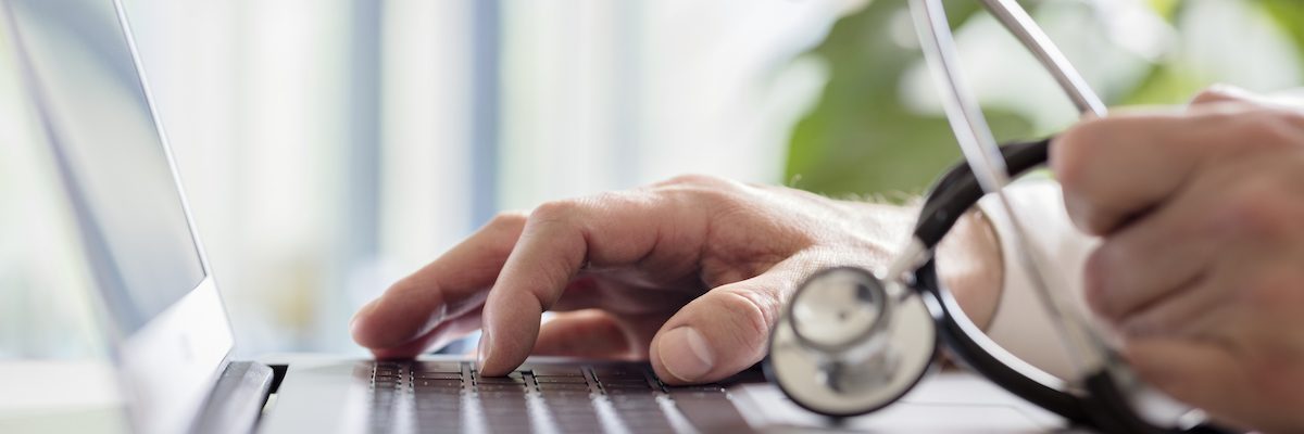 Doctor entering patient notes on a laptop in surgery